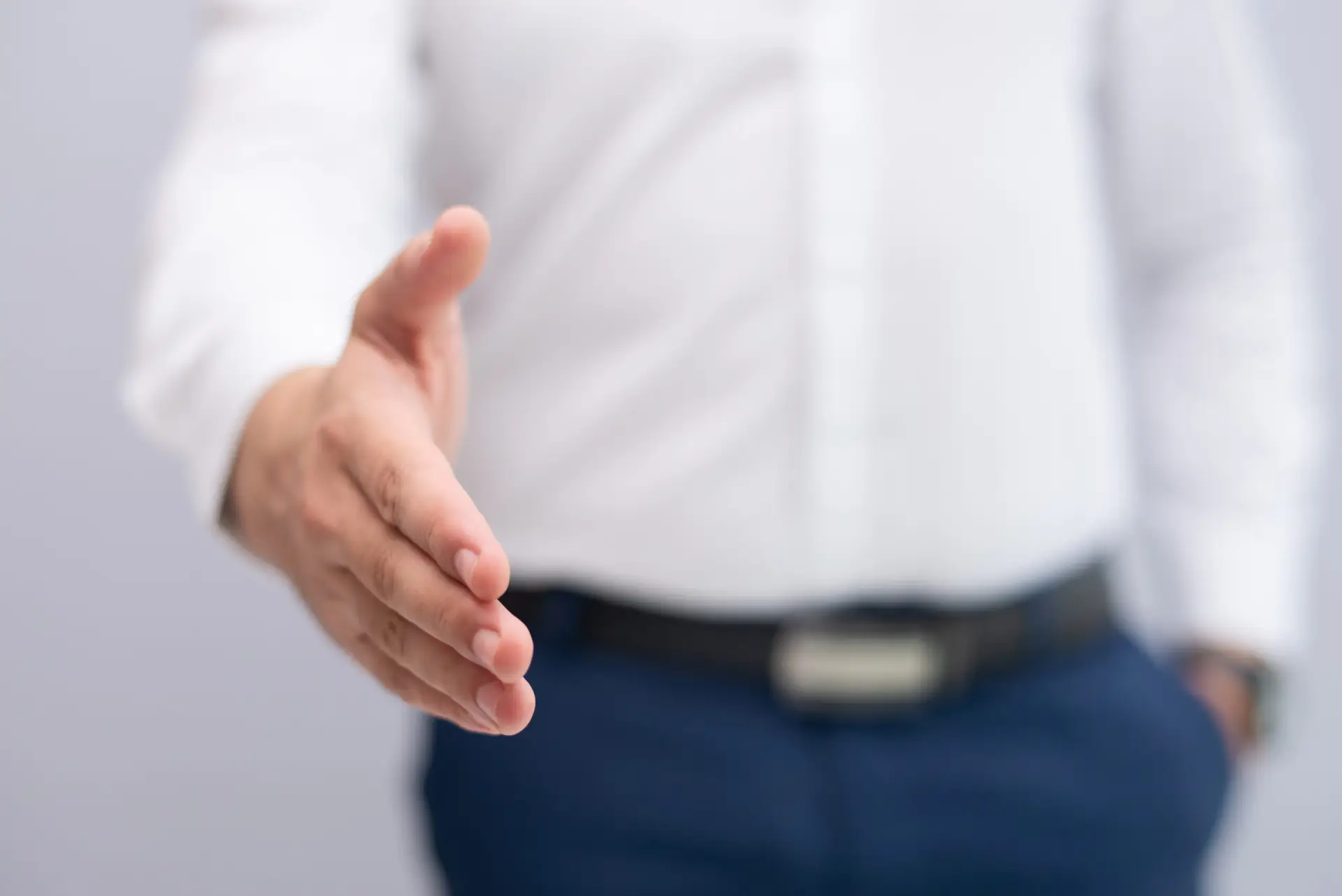 Close-up of businessman stretching hand for handshake. Caucasian manager greeting client or partner. Partnership concept